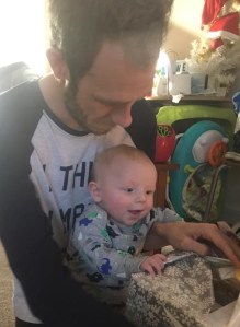 Daddy helping Robbie open his first ever Christmas present