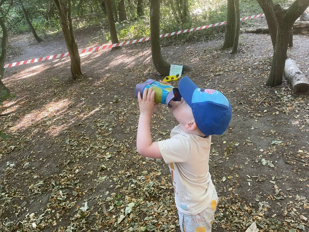 A child looking through binoculars in the woods